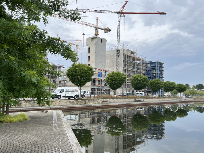 Im Neckarbogen sind große Baukräne vor hohen Gebäuden im Rohbau zu sehen. 