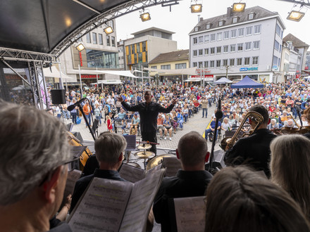 Das Bild zeigt einen Chor mit Orchester auf der Bühne am gut gefüllten Kiliansplatz bei Magie der Stimmen. 