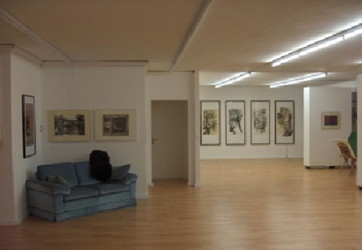 Blick in die Ausstellungsräume der Kunstetage K55: Das Bild zeigt einen Innenraum des Künstlerbunds Heilbronn. Der Raum ist hell und offen gestaltet, mit einem Holzfußboden und weißen Wänden. An den Wänden hängen mehrere gerahmte Kunstwerke, vor allem grafische Arbeiten. Links steht ein Sofa, das zum Verweilen einlädt. Die Atmosphäre wirkt ruhig und konzentriert und bietet Raum zur Betrachtung der ausgestellten Kunst. 
