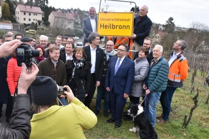 Thomas Strobl, stellvertretender Ministerpräsident und Innenminister, und Heilbronns Oberbürgermeister Harry Mergel tauschen das erste Ortsschild mit der Zusatzbezeichnung Universitätsstadt aus