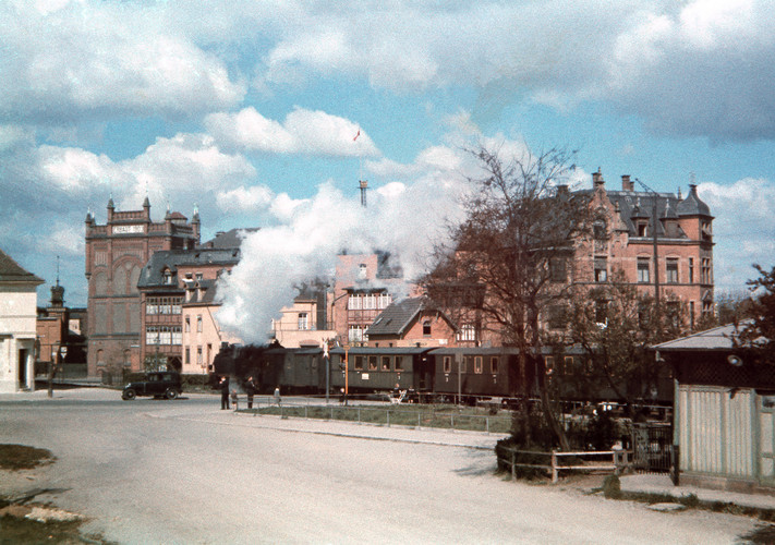 Das Bild zeigt eine Dampflok, die um das Jahr 1940 vom Südbahnhof mit Personenwaggons Richtung Sontheim fährt. Im Hintergrund sind Werksgebäude der Firma Knorr zu sehen. Das Gebäude rechts wurde 1898 erbaut. In den 1930er Jahren war dort die Gaststätte "Fleinerhöhe".