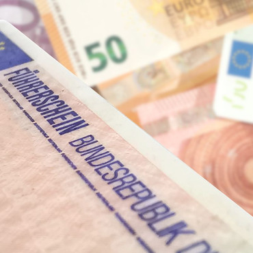 Ein deutscher Führerschein liegt neben Euro Geldscheinen im Hintergrund.
