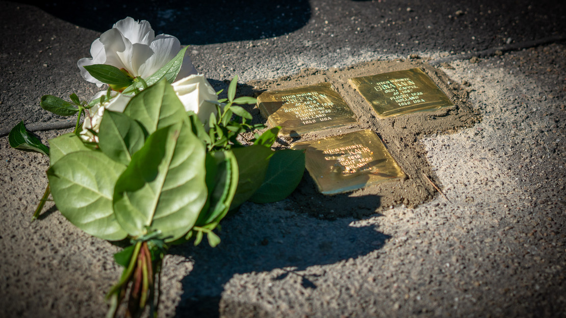 Weiße Blume liegt neben neu verlegten Stolpersteinen in Heilbronn die an Opfer des Nationalsozialismus erinnern eingebettet im Gehweg einer Straße