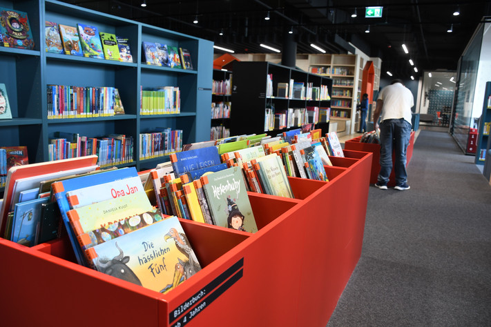 Das Bild zeigt den Teil der Stadtbibliothek mit den Bilderbüchern in den Regalen. Hier ist die Ausleihquote besonders hoch..