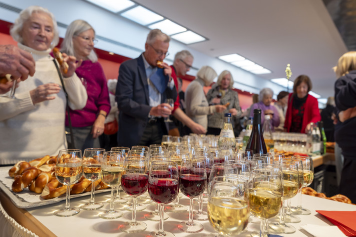 Das Bild zeigt Gäste nach dem offiziellen Programm, die sich mit Getränken und Snacks im Foyer versorgen.