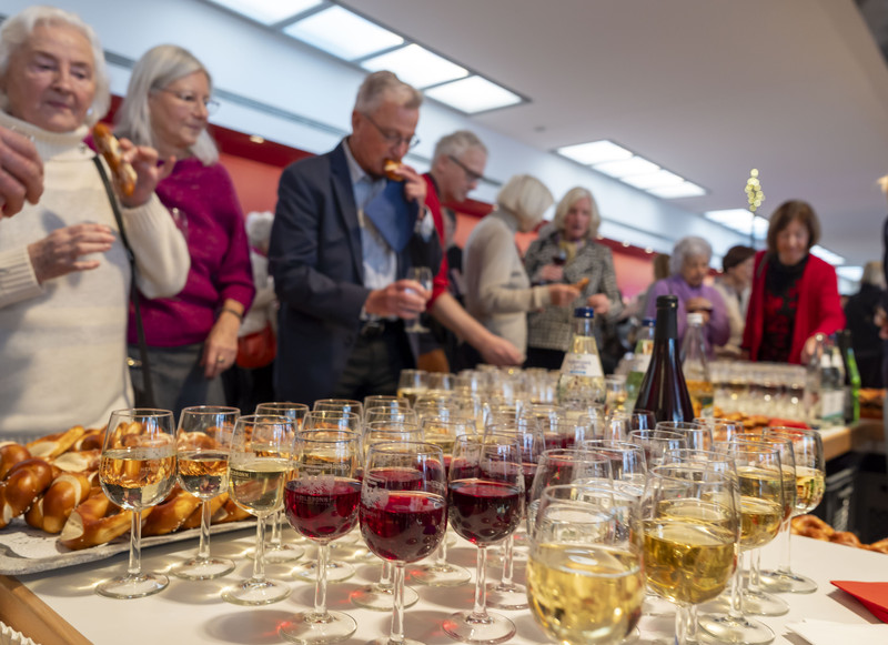Das Bild zeigt Gäste nach dem offiziellen Programm, die sich mit Getränken und Snacks im Foyer versorgen.