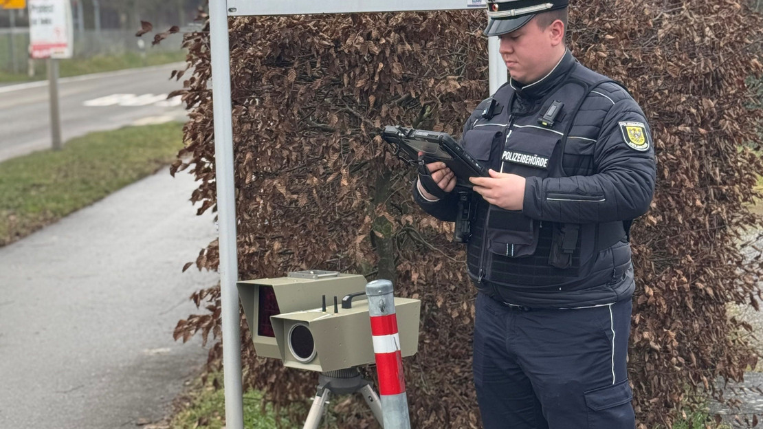 Auf dem Bild ist ein Mitarbeiter der Stadt mit einem mobilen Tempo-Messgerät am Straßenrand zu sehen. 