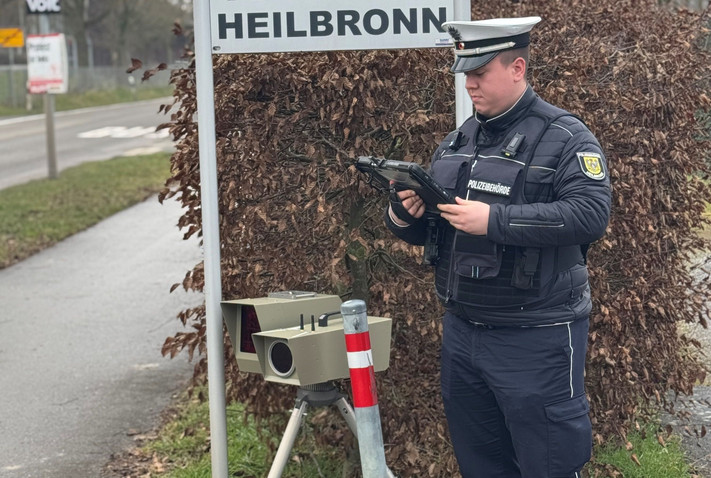 Auf dem Bild ist ein Mitarbeiter der Stadt mit einem mobilen Tempo-Messgerät am Straßenrand zu sehen. 
