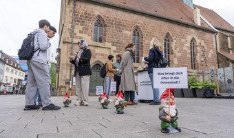 Das Bild zeigt den Infostand der Bürgerbeteilgung in der Sülmerstraße. Dort kommen Mitarbeitende der Stadt mit Bürgerinnen und Bürgern zur Entwicklung der Innenstadt und des neuen Quartiersbüros ins Gespräch. Zwergfiguren mit Fragen zur Innenstadt machen auf den Stand aufmerksam. 