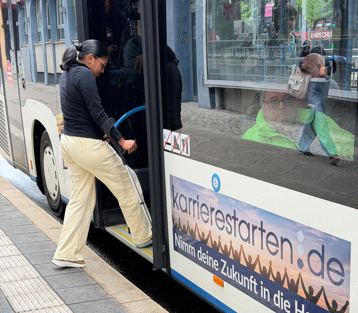 Frau mit Krücke beim Einsteigen in einen Bus an einer barrierefreien Bushaltestelle