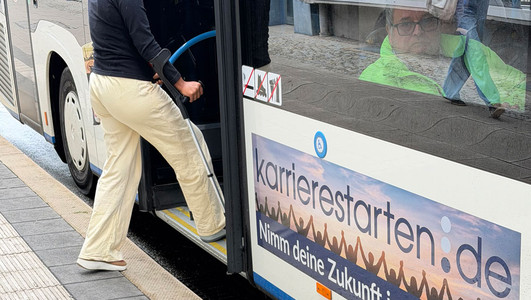 Frau mit Krücke beim Einsteigen in einen Bus an einer barrierefreien Bushaltestelle
