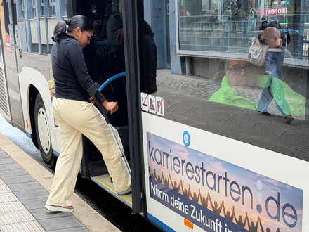 Frau mit Krücke beim Einsteigen in einen Bus an einer barrierefreien Bushaltestelle