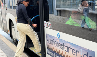 Frau mit Krücke beim Einsteigen in einen Bus an einer barrierefreien Bushaltestelle