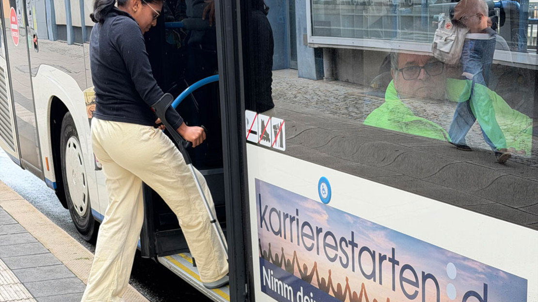 Frau mit Krücke beim Einsteigen in einen Bus an einer barrierefreien Bushaltestelle