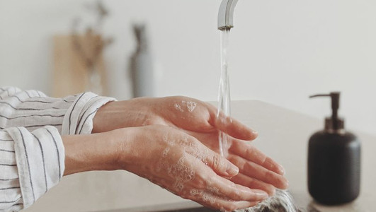 Frau, die sich an einem Waschbecken die Hände wäscht. 