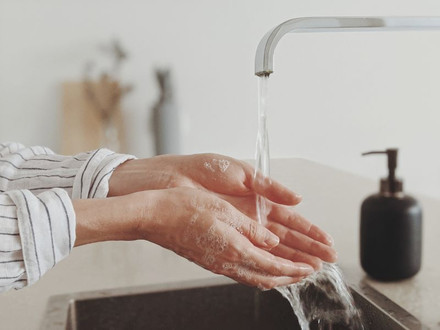 Frau, die sich an einem Waschbecken die Hände wäscht.