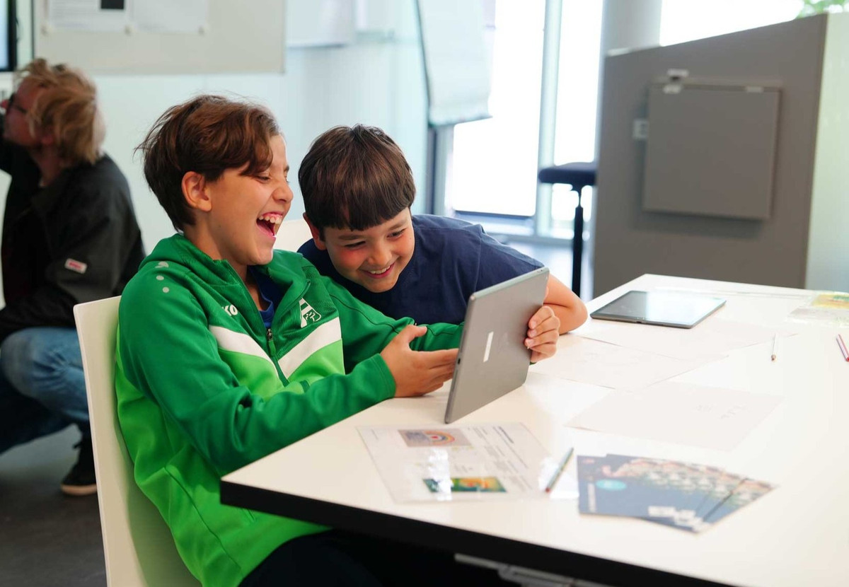Man sieht zwei Jungen, die Spaß am Tablet haben.