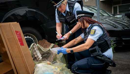 Das Bild zeigt eine Streife der Waste Watcher mt zwei Frauen, die illegal abgelegten Müll nach Hinweisen auf den Verursacher durchsuchen. 