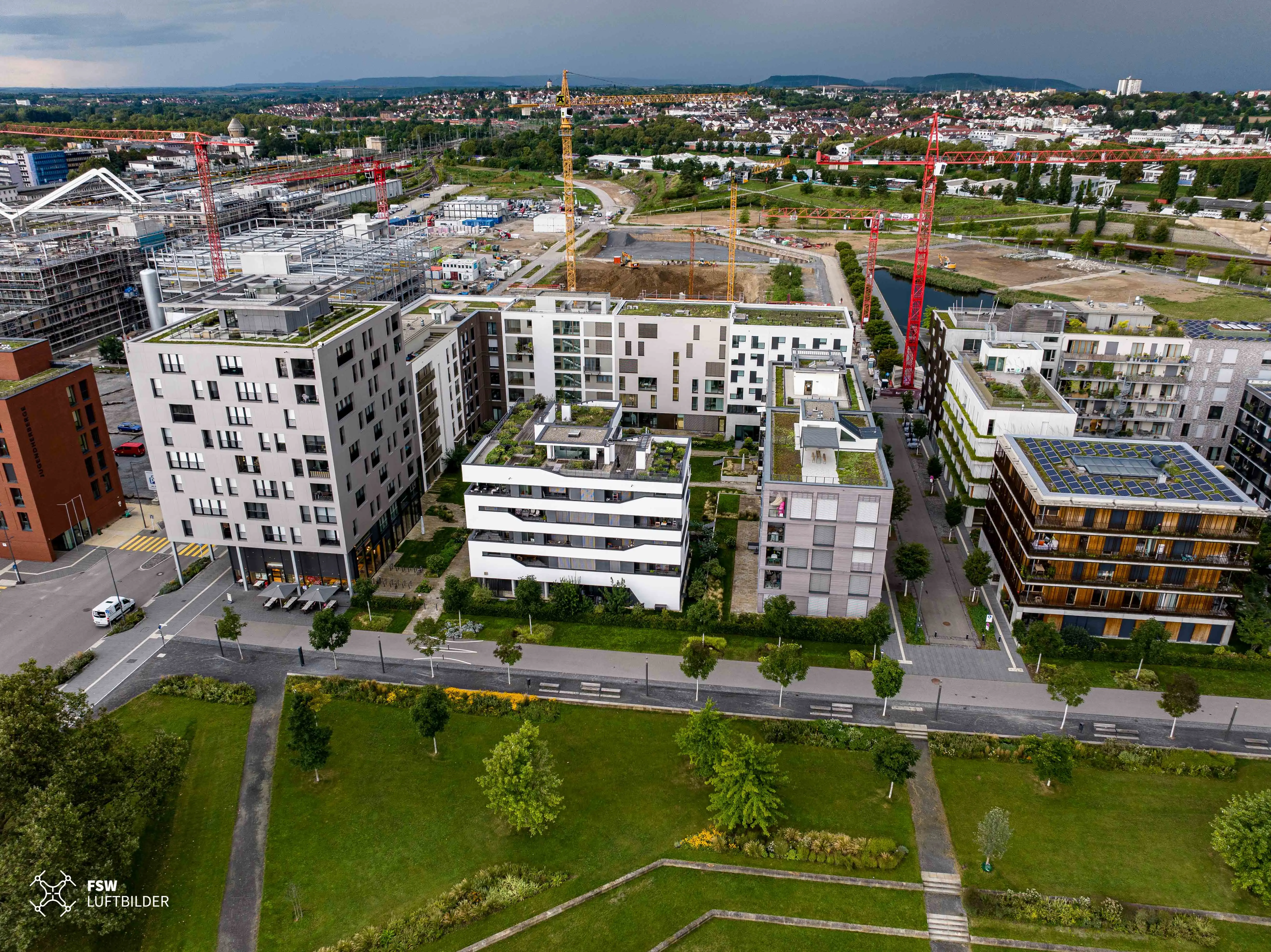 Hinter dem 1. Bauabschnitt ragen die Krane in die Höhe. Bereits heute wohnen im Neckarbogen ca. 600 Menschen.