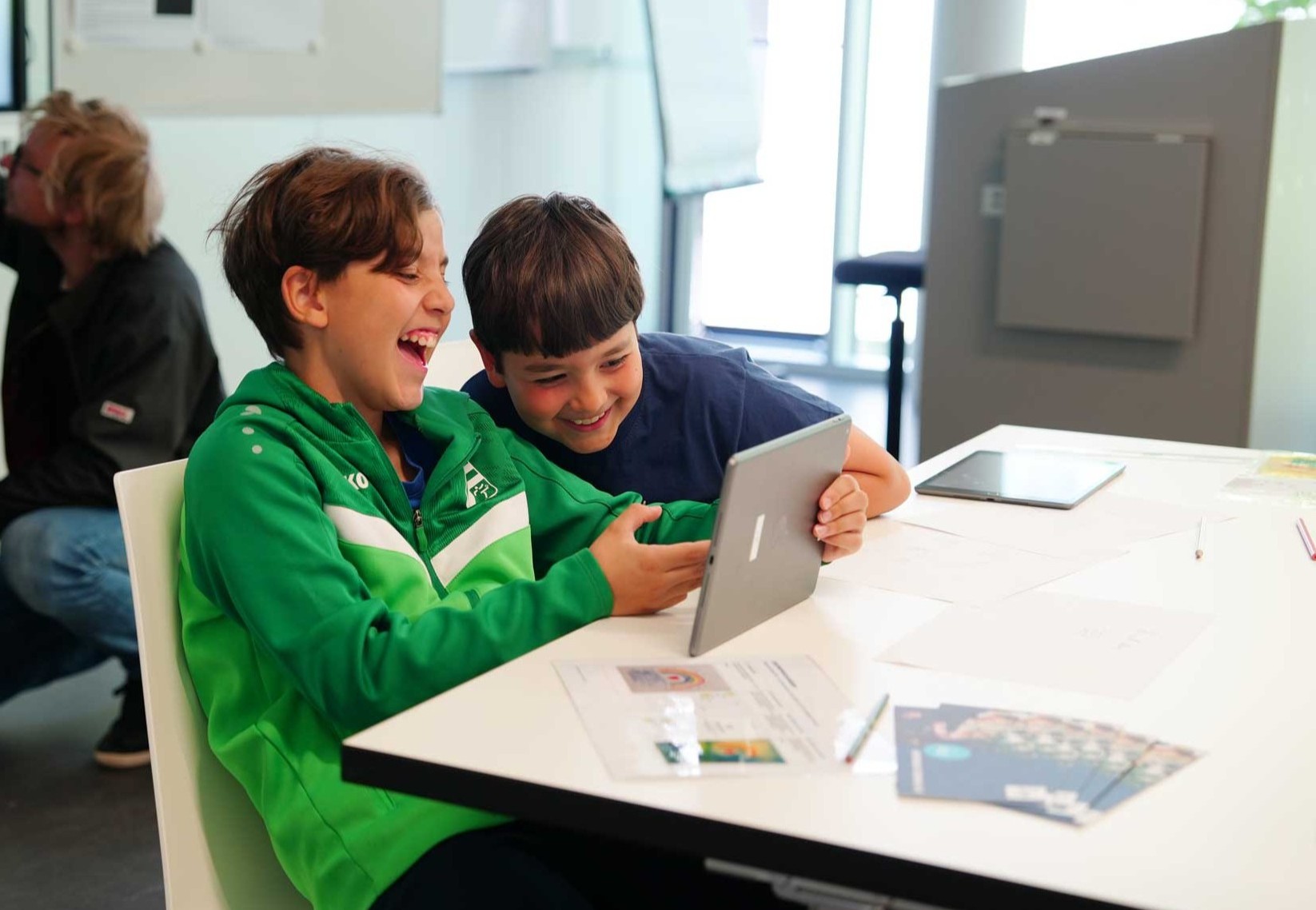 Man sieht zwei Jungen, die Spaß am Tablet haben.