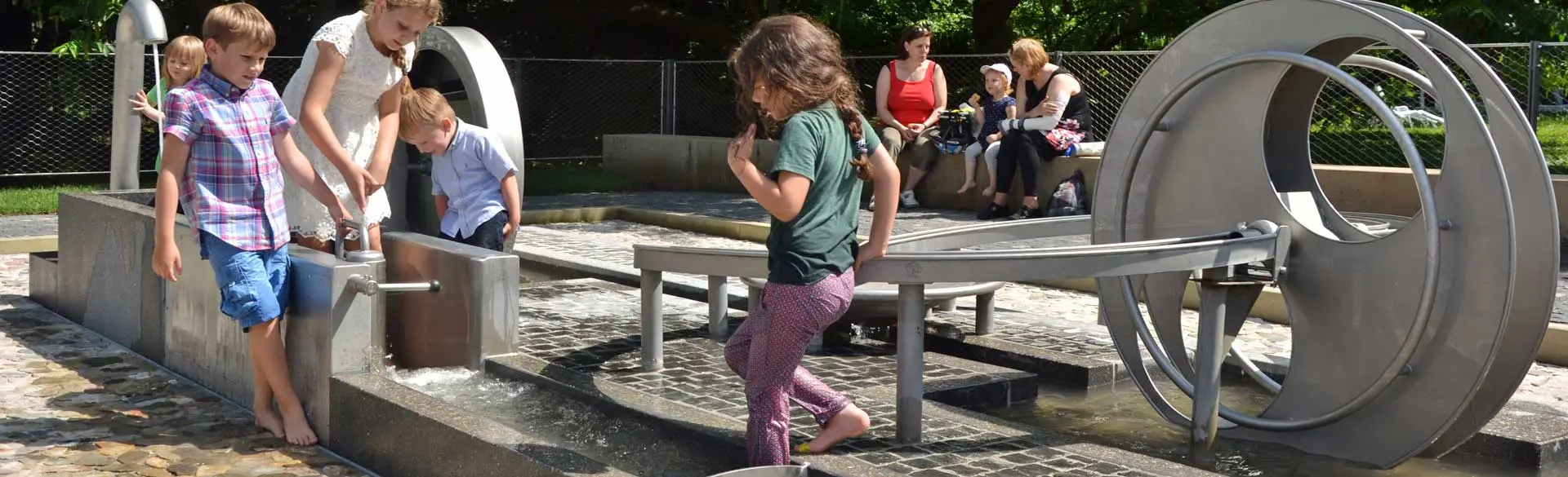 Man sieht spielende Kinder am Wasserspielplatz vor der experimenta.