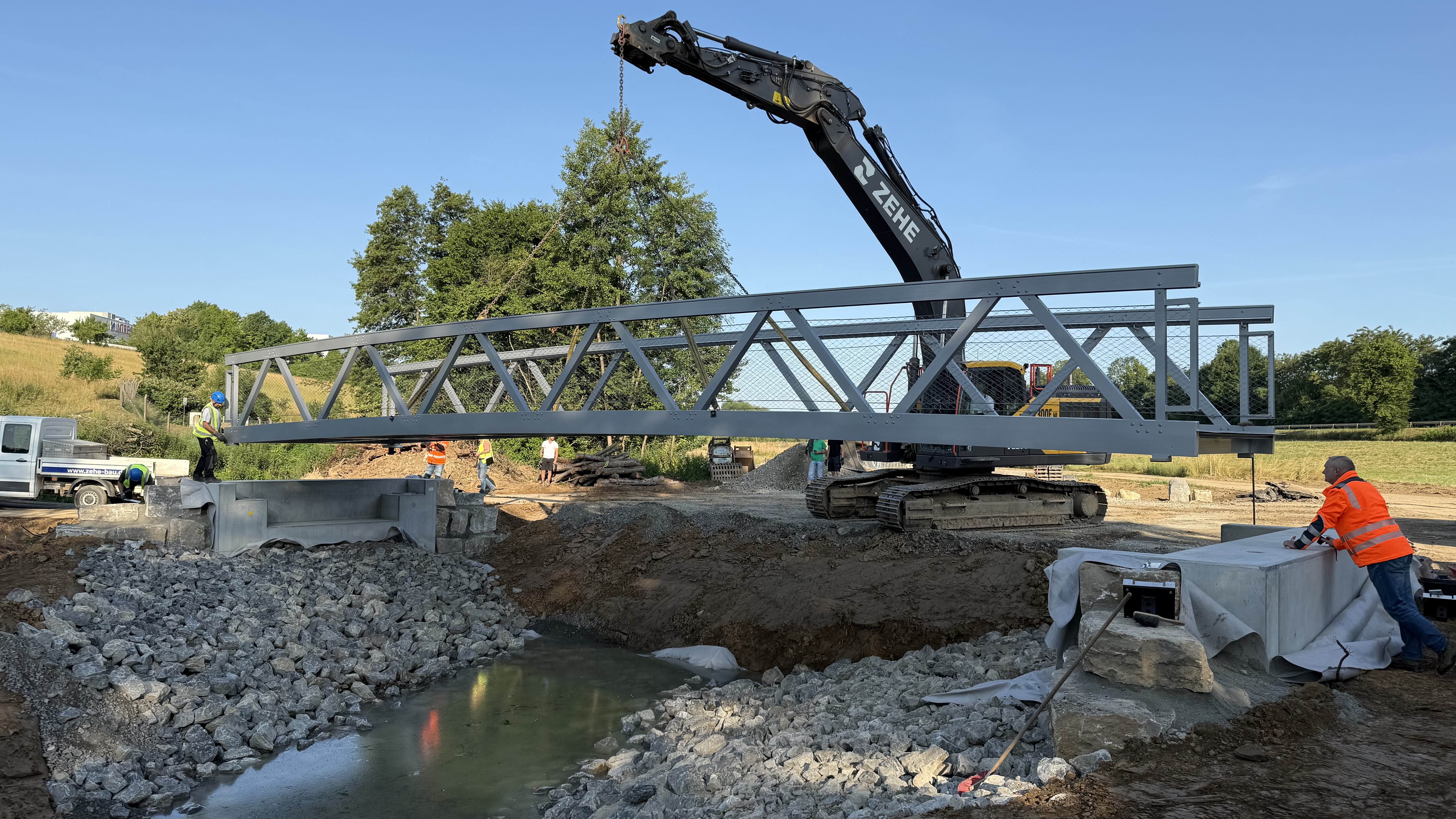 Routiniert lassen die Männer der Baufirma die knapp fünf Tonnen schwere Aluminiumbrücke am Böllinger Bach einschweben. Foto: Klöppel