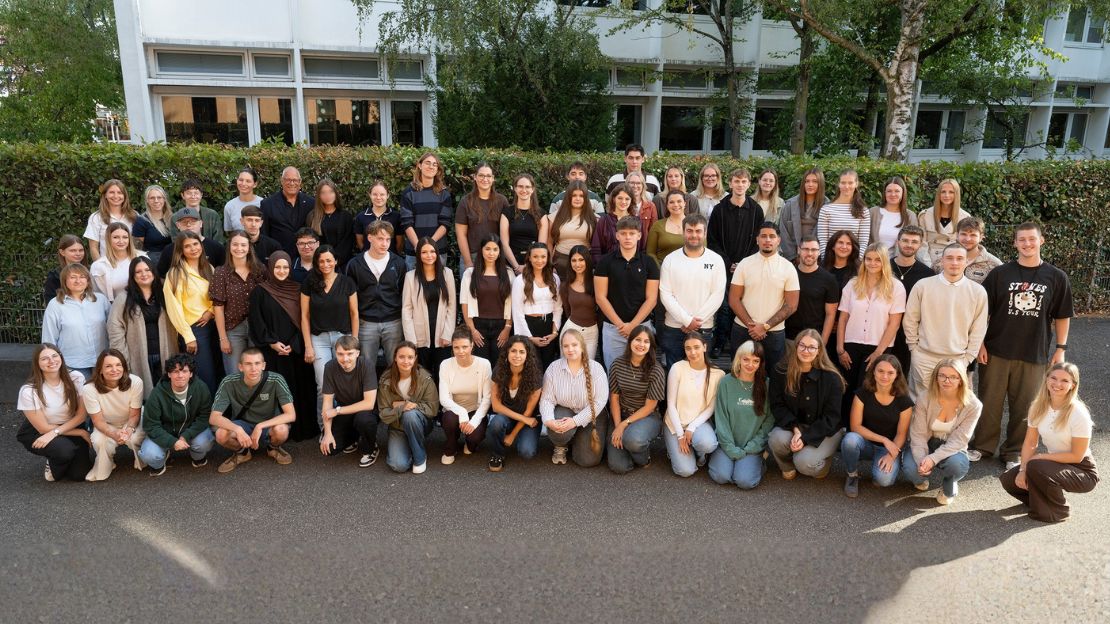 Eine große Gruppe neuer Auszubildender und Studierender der Stadt Heilbronn steht gemeinsam im Freien vor einem Gebäude.