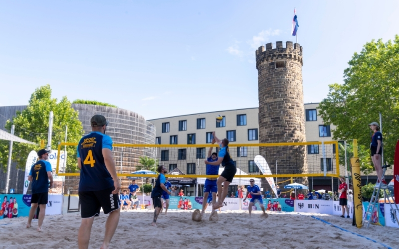 Ein Team spielt Beachvolleyball auf einem Feld vor dem Bollwerksturm