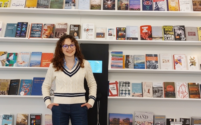 Junge Frau steht vor Bücherregal
