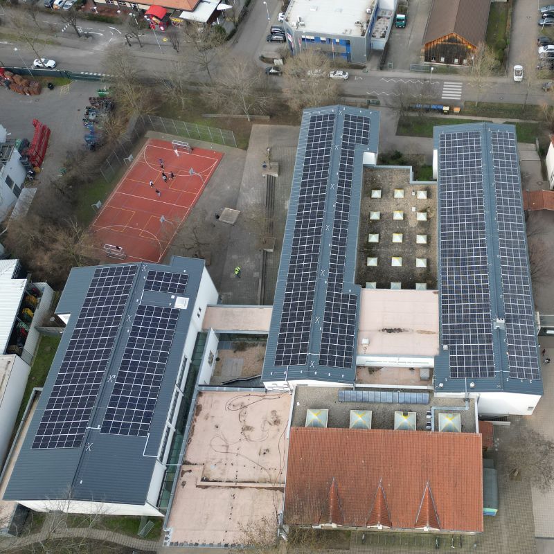 Ein Luftbild. Man sieht die Photovoltaikanlagen auf dem Dach der Schule.