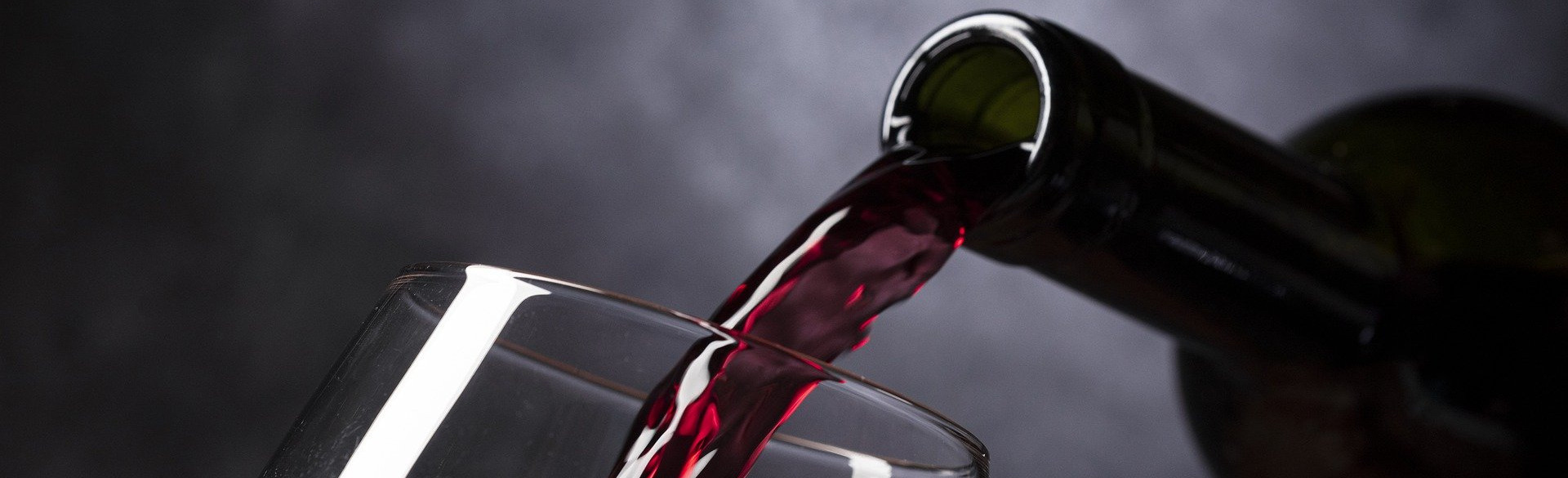 Rotwein wird in ein Glas eingeschenkt