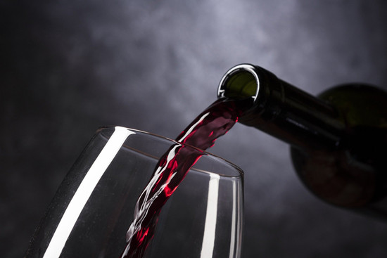 Rotwein wird in ein Glas eingeschenkt