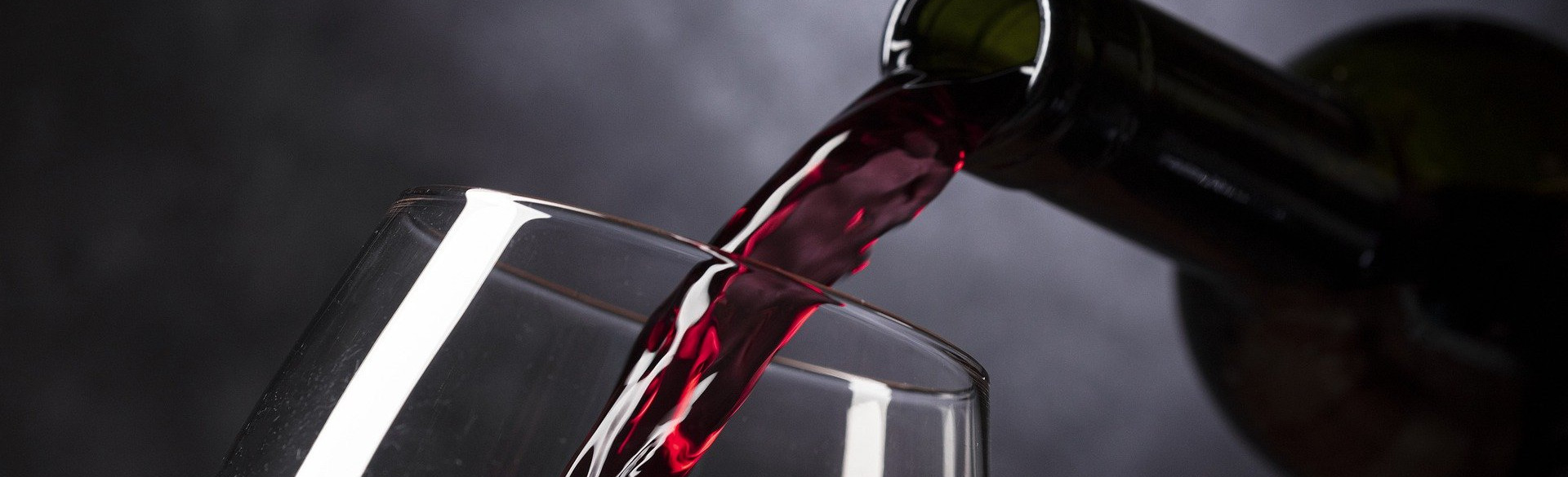 Rotwein wird in ein Glas eingeschenkt